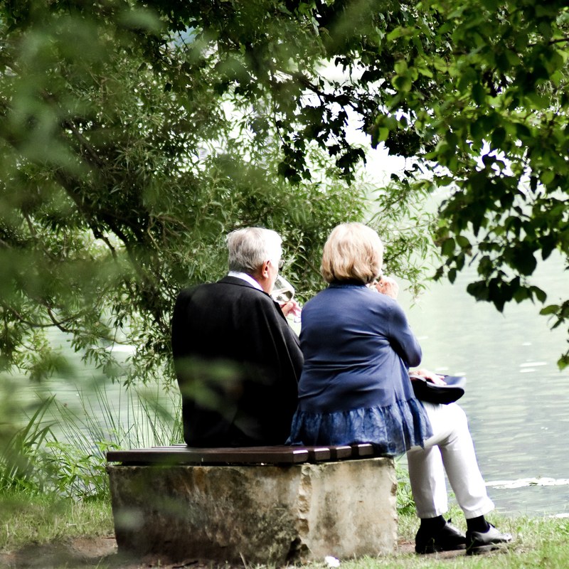 Älteres Paar sitzt gemeinsam an einem See